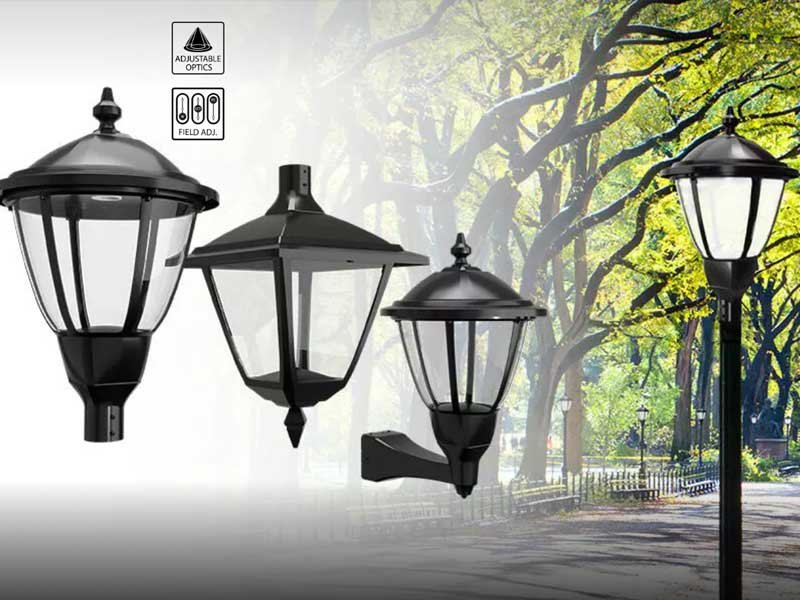 Four black outdoor lantern-style light fixtures are shown against a park background with trees and a walking path. Icons indicate adjustable optics and field adjustment features.